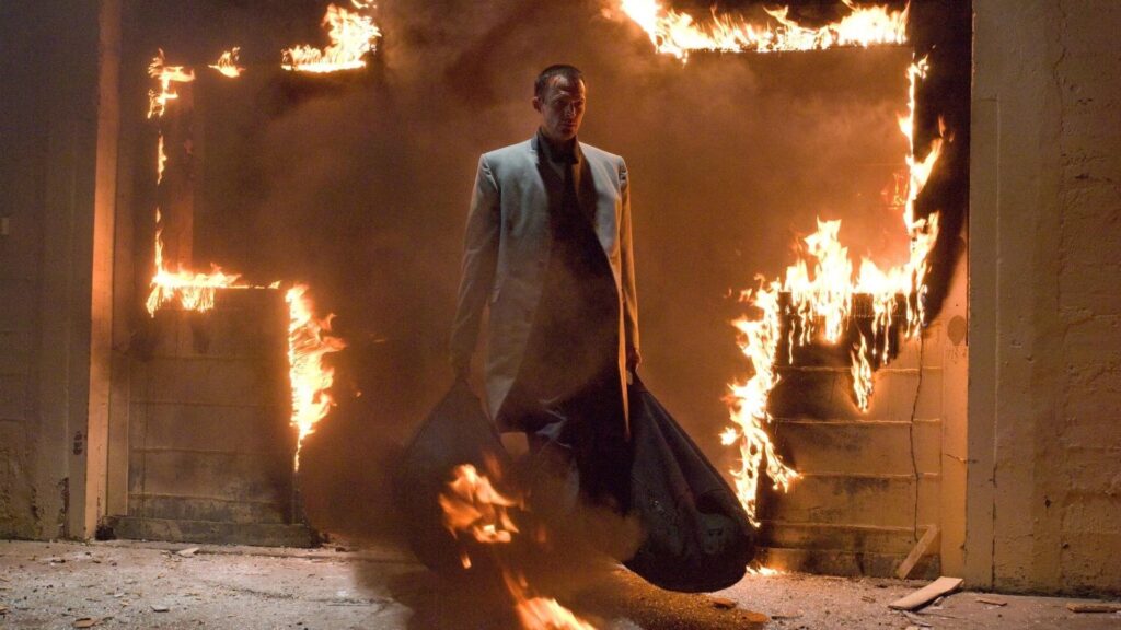 Paul Bettany as the ex-angel Michael emerges from a burning building with plenty of guns.